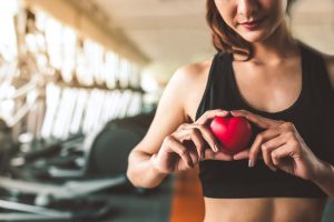 Happy sport woman holding red heart