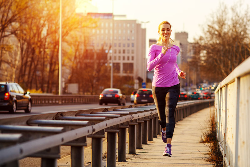 Young beautiful woman running on the sidewalk