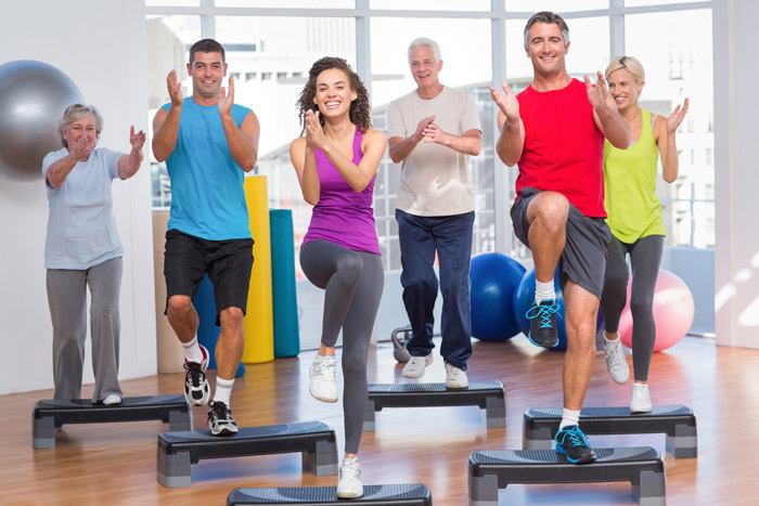 People performing step aerobics exercise in gym